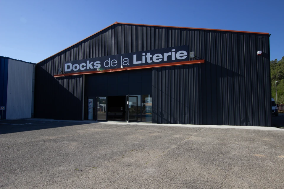 Grand magasin de literie avec allées centrales présentant des matelas et sommiers sur structures d'exposition en bois